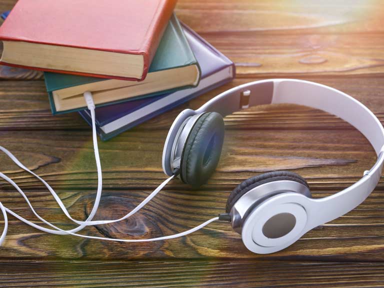 Headphones plugged into book to represent audiobooks