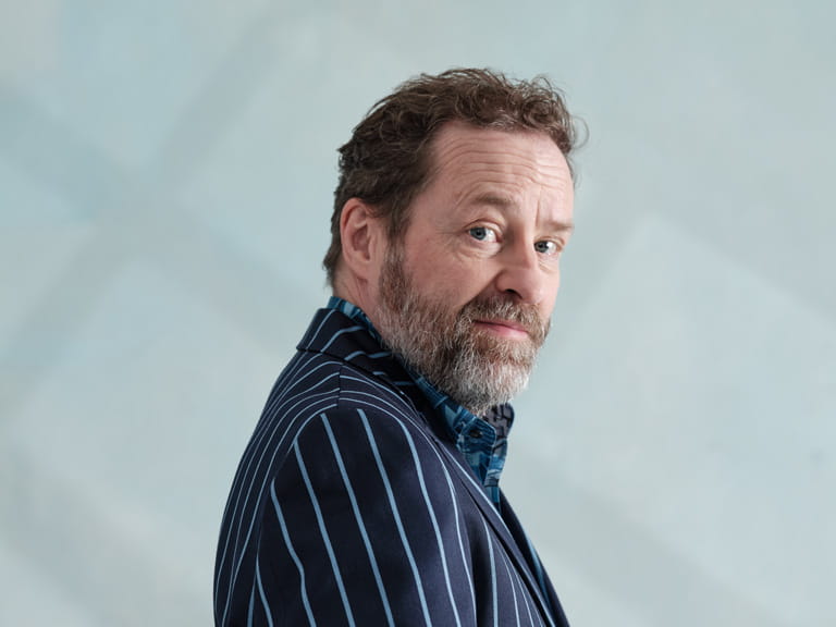 Ardal O'Hanlon side on looking at the camera