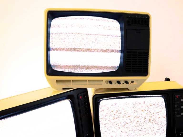 A stack of retro TVs with static on their screens