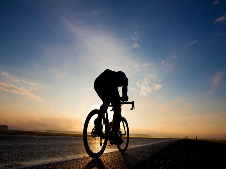 A cyclist rides into the sunset to represent Mavis Paterson's epic bike ride