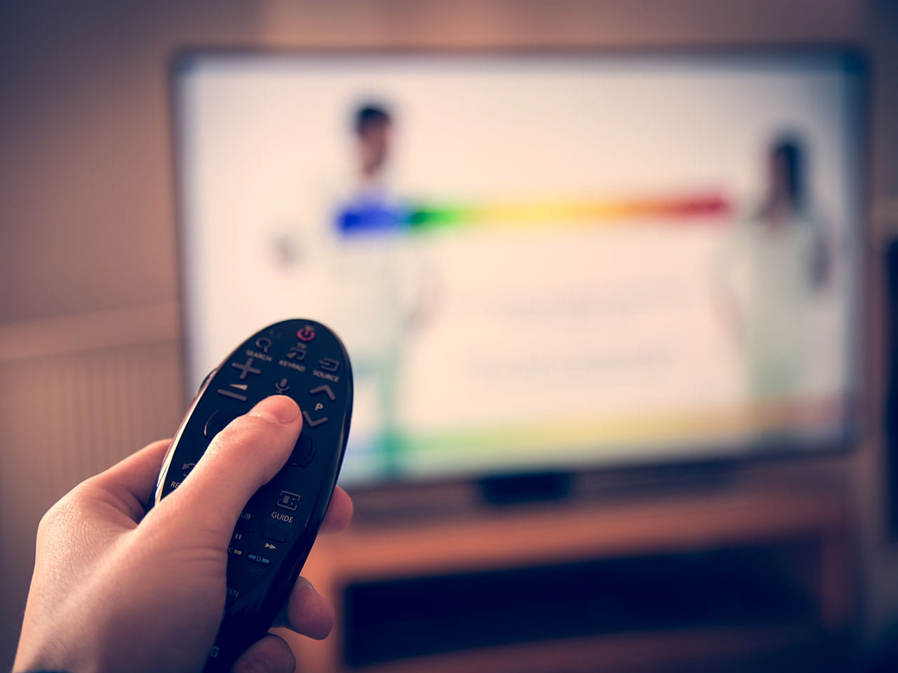 Remote control being used with TV in the background