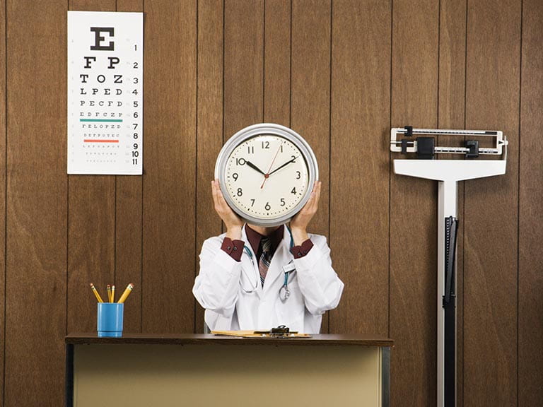 Doctor sitting in surgery holding up clock face