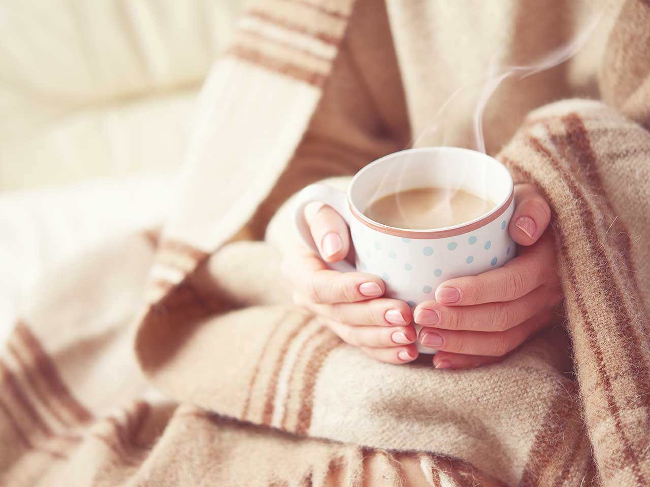 Woman wrapped in blanket warming hands