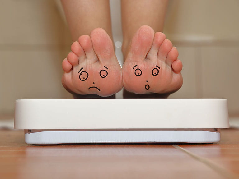 Woman on scales with faces drawn on toes