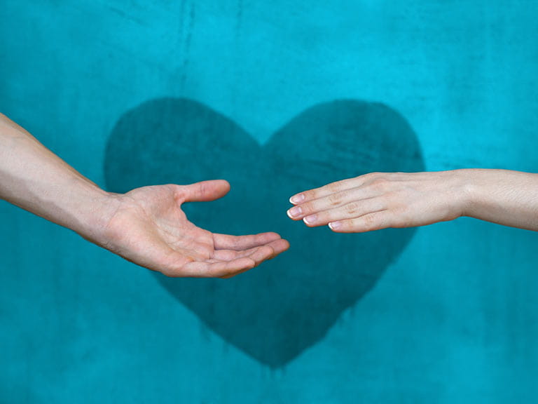 Hands reaching out to hold against a heart background