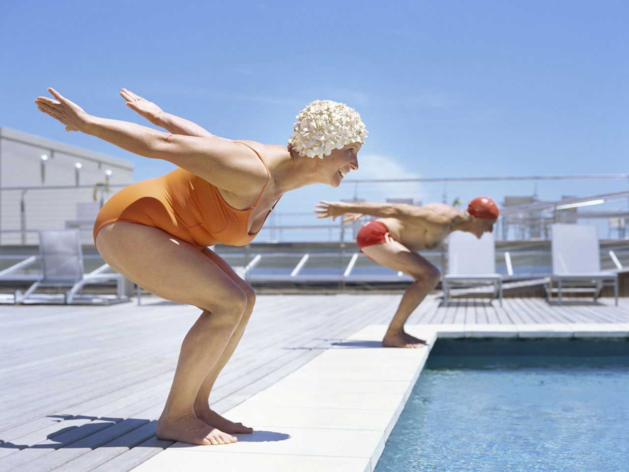 Mature couple diving into a pool to have a race