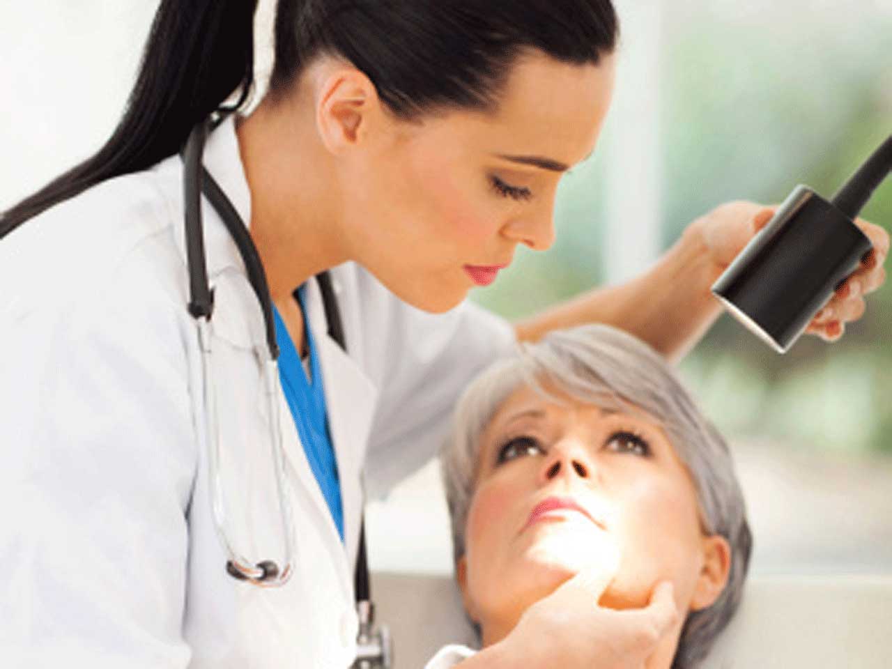 Dermatologist examining a female patient's skin