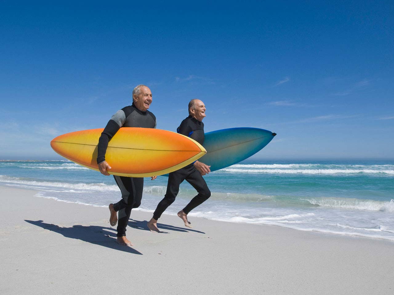 Two mature men running on the beach laughing
