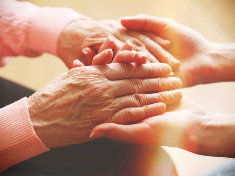 An older lady's hands being held by a younger lady