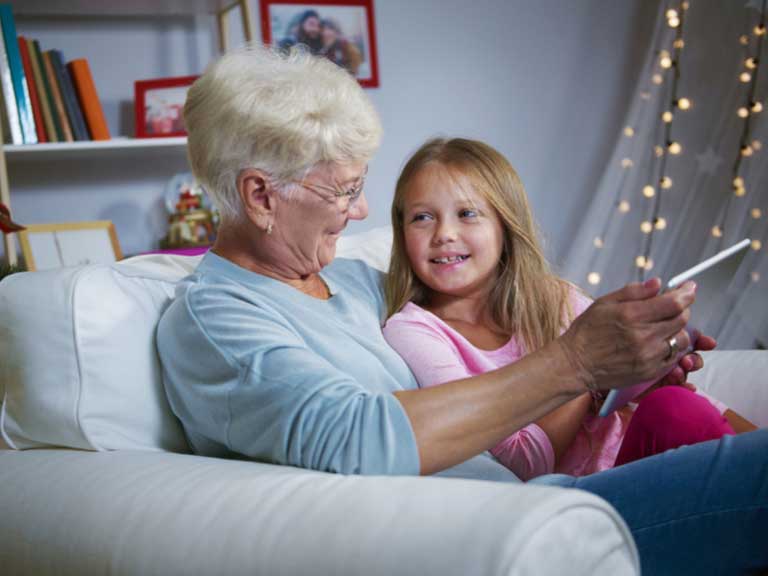 Grandmother and granddaughter sitting happily together on a sofa