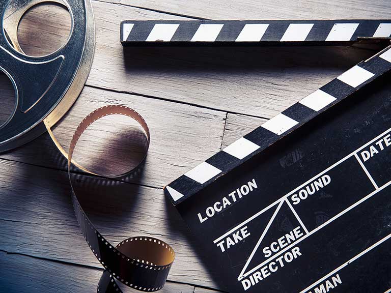 A clapboard and vintage film real to represent working as an extra