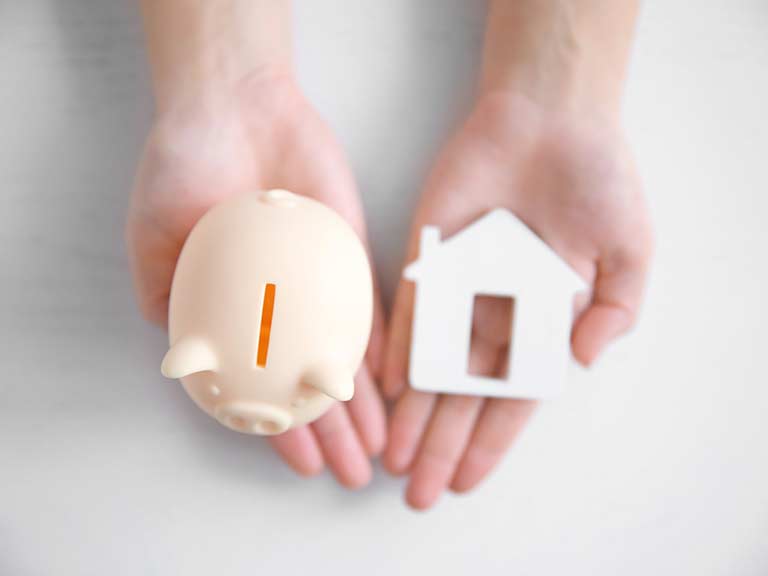A piggy bank and a house next to each other to represent returning a deposit after renting