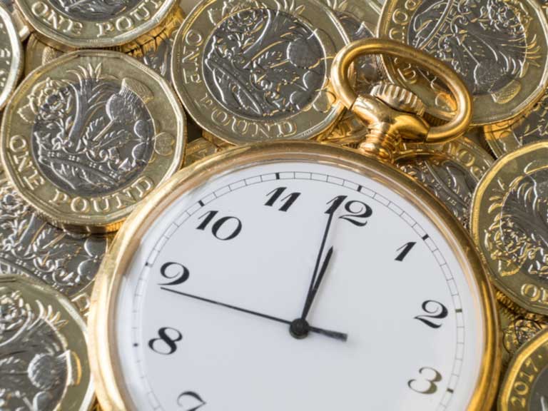 Pocket watch placed over layers of £1 coins
