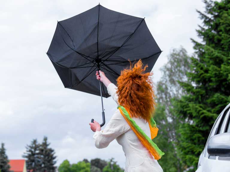 Woman holding an umbrella that has been turned inside out by a strong gust of wind