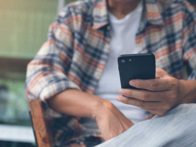 Man sitting in chair looking at mobile phone 