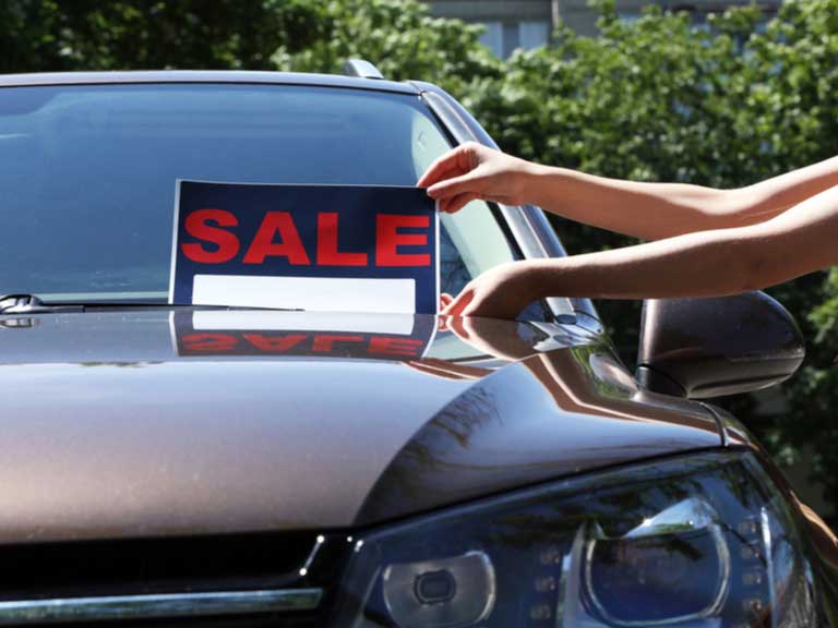 For sale sign being placed on a car windscreen