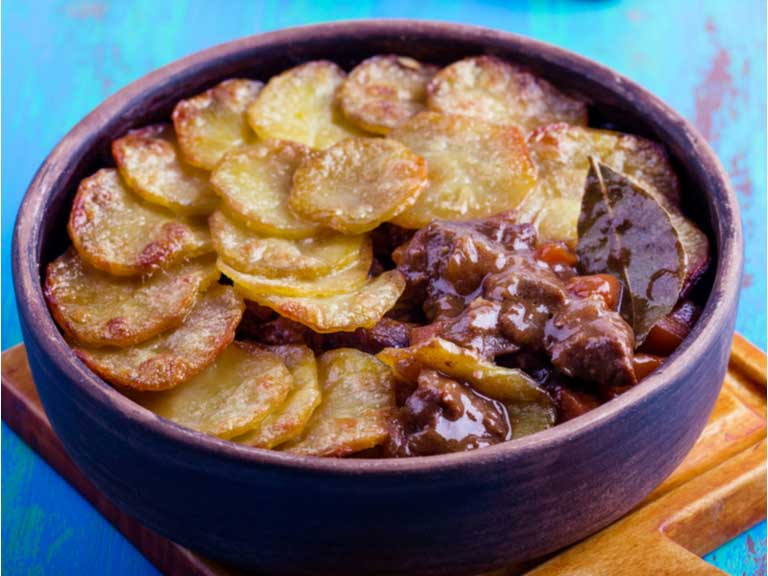 Lancashire hotpot with one spoonful removed showing the stew beneath