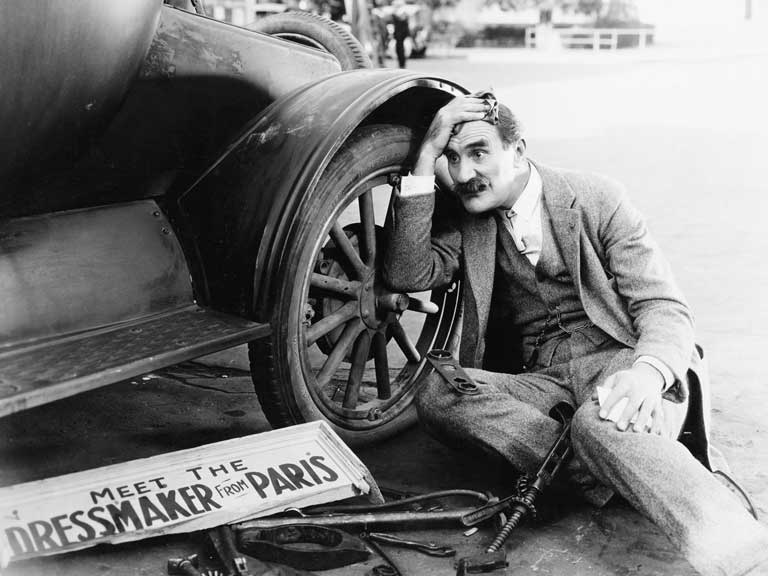 Retro image of a man with a broken down vintage car