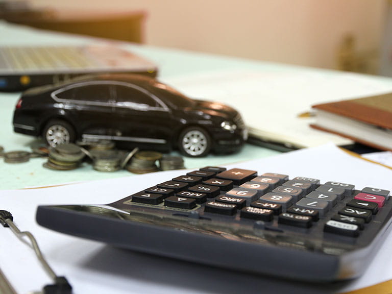 A model car next to a calculator to represent a UK car that's the cheapest to run