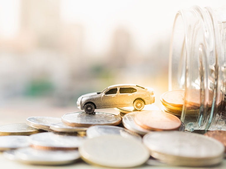 A model car perched on coins to represent the UK's cheapest cars to run