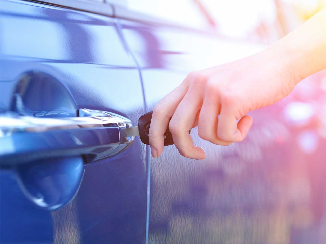 Hand turning a key in a car door to represent buying and selling cars