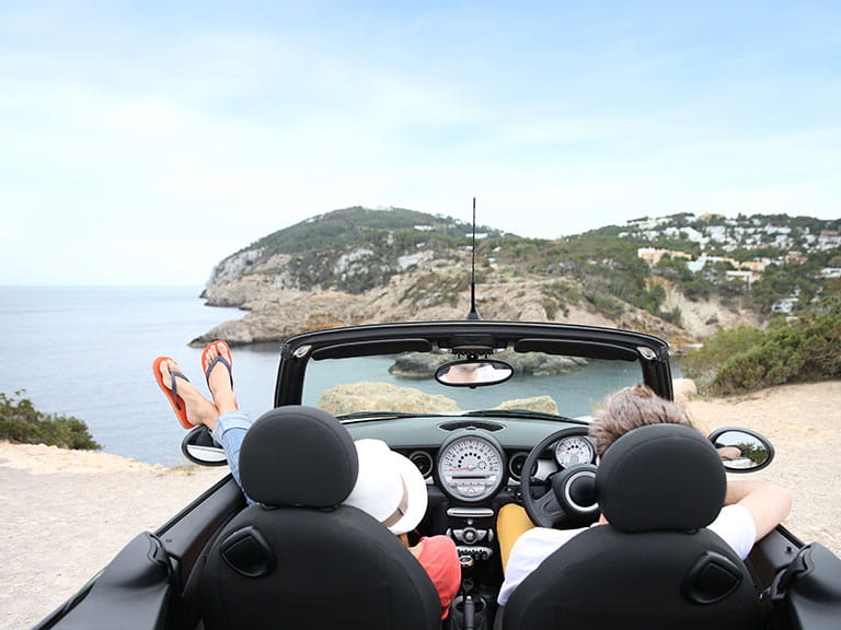 A couple enjoy the views from their convertible car