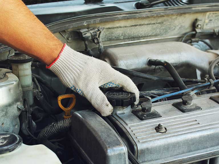 A man changes the oil in the engine to keep the car running