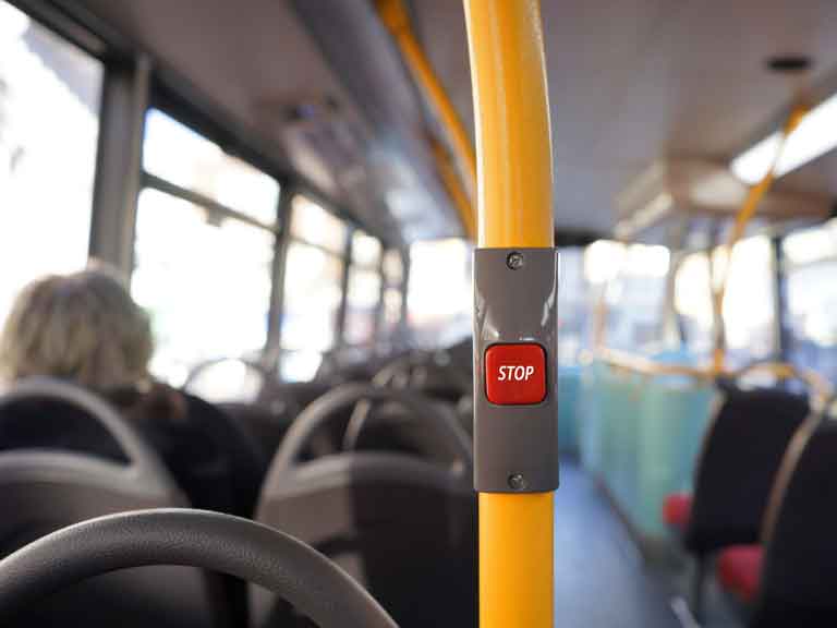 Interior of bus focusing on the bus bell with the word Stop on it. 