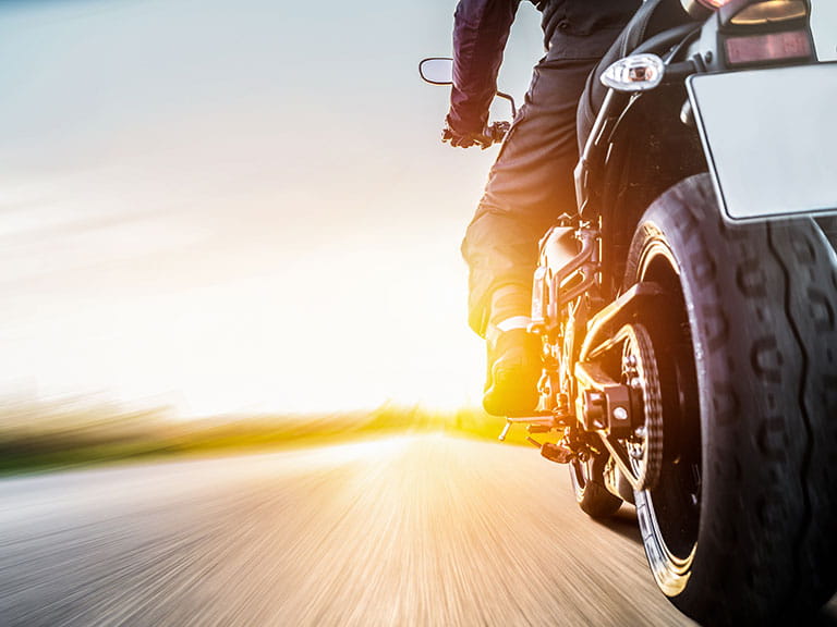 A rider rides a motorbike into the sunset to represent born again bikers
