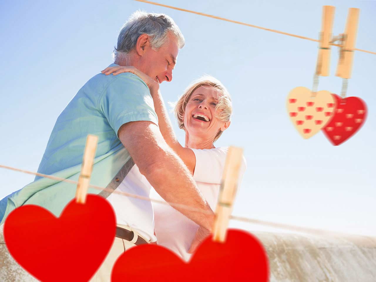 Mature couple laughing with love hearts around them