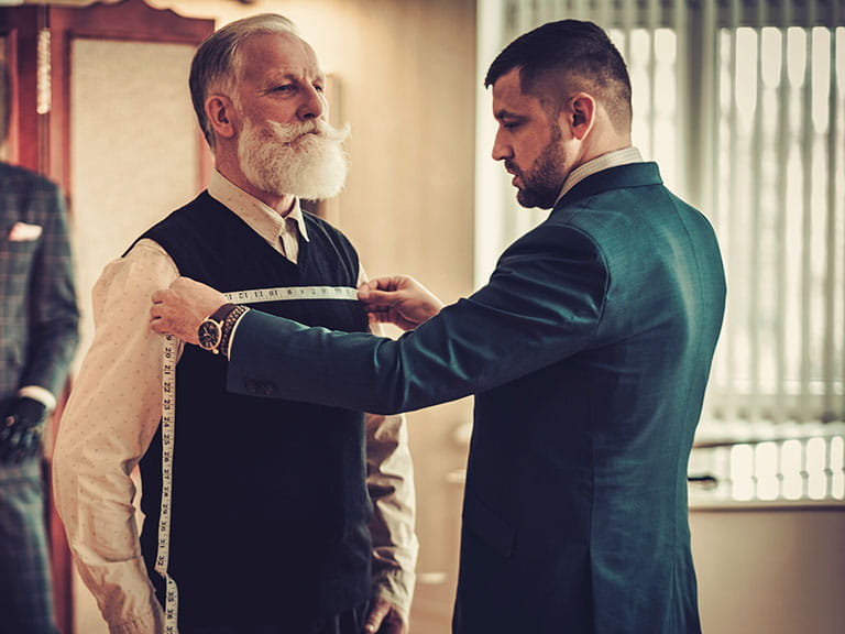 A man gets measured for his bespoke tailored suit