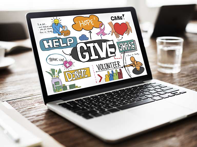 A laptop open with charity images on the screen to represent setting up a charity event page on Facebook