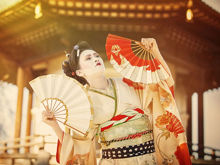 A Japanese Geisha dancing near a pagoda