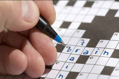A hand filling out a crossword