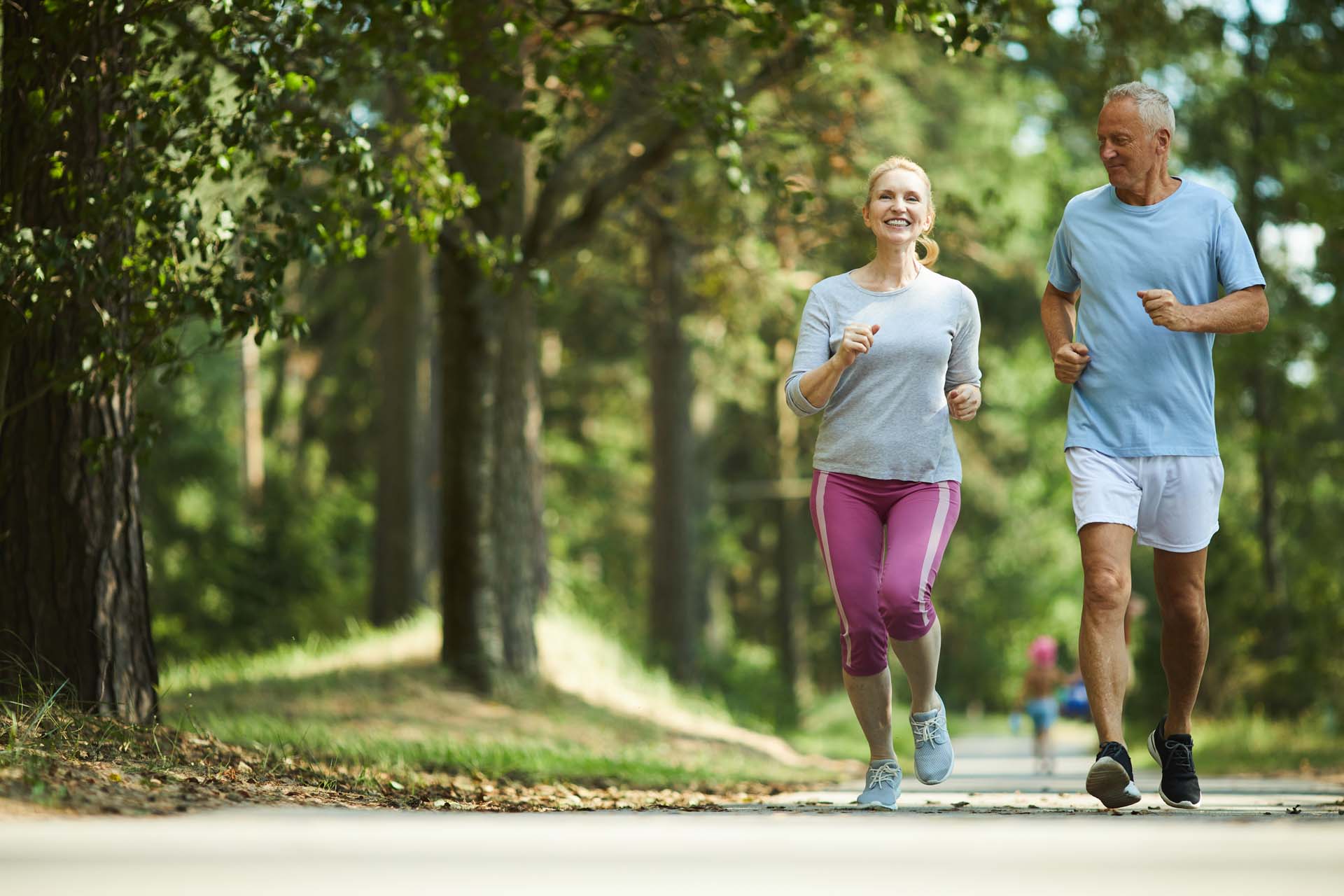 a man and woman smiling and running through woodland