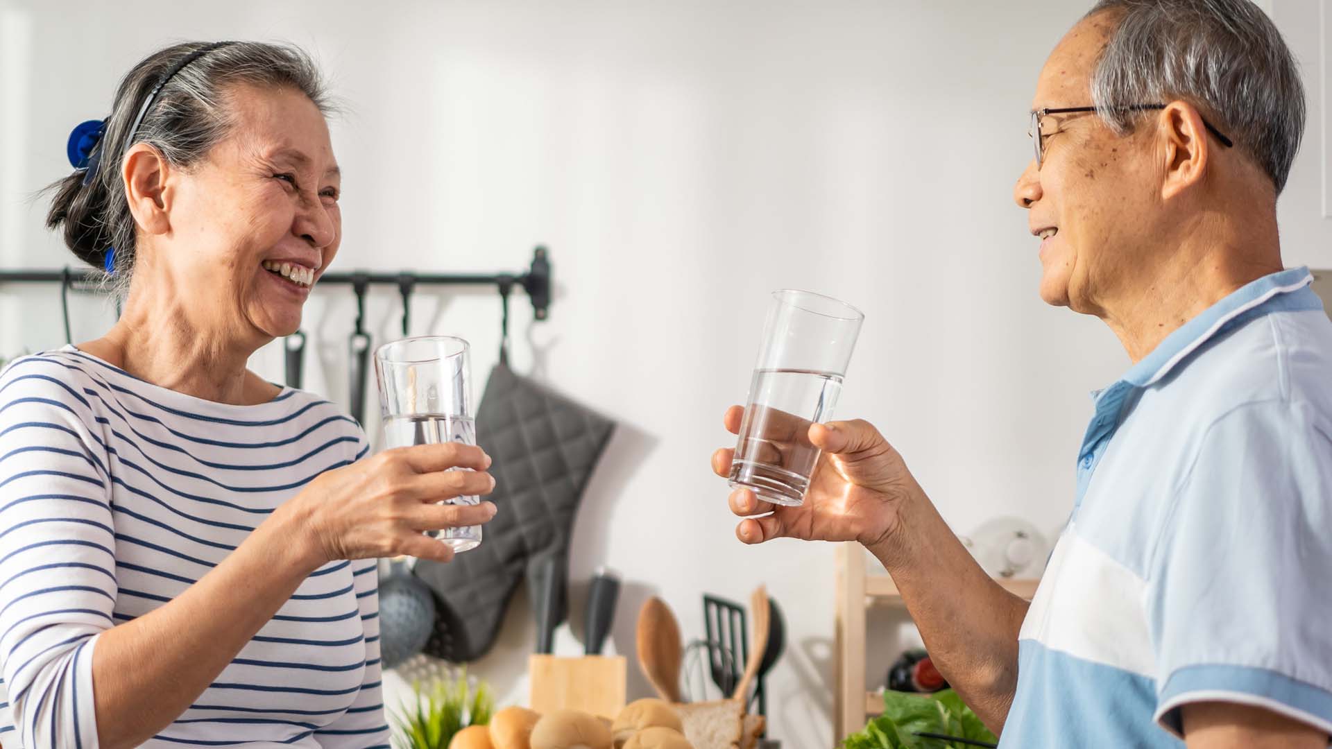 An older couple with glasses of water in their hands