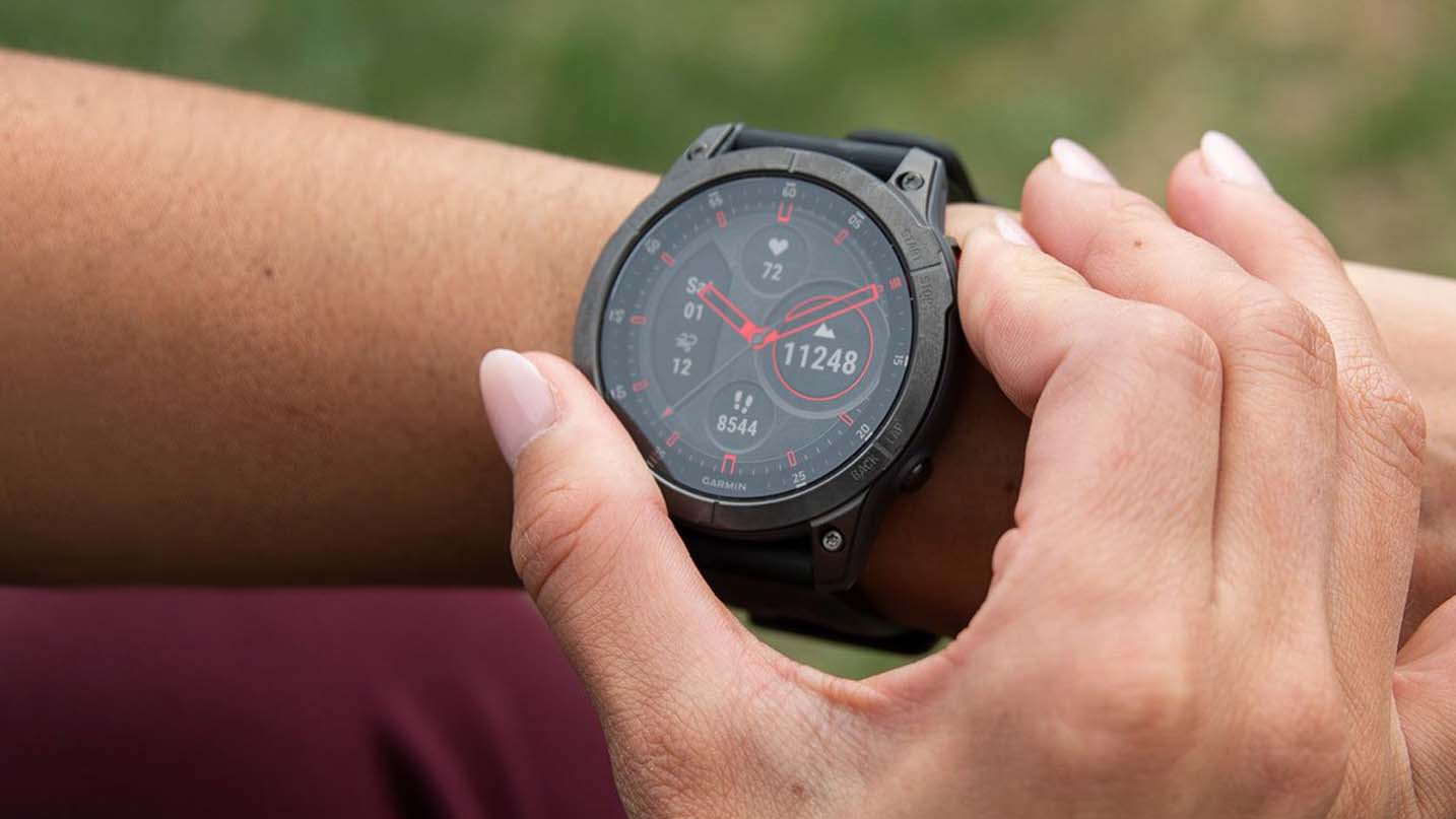 A close up of a man adjusting a smartwatch on his arm