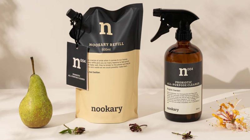 A refill packet of Nookary eco-friendly cleaning products next to a reusable bottle and a pear