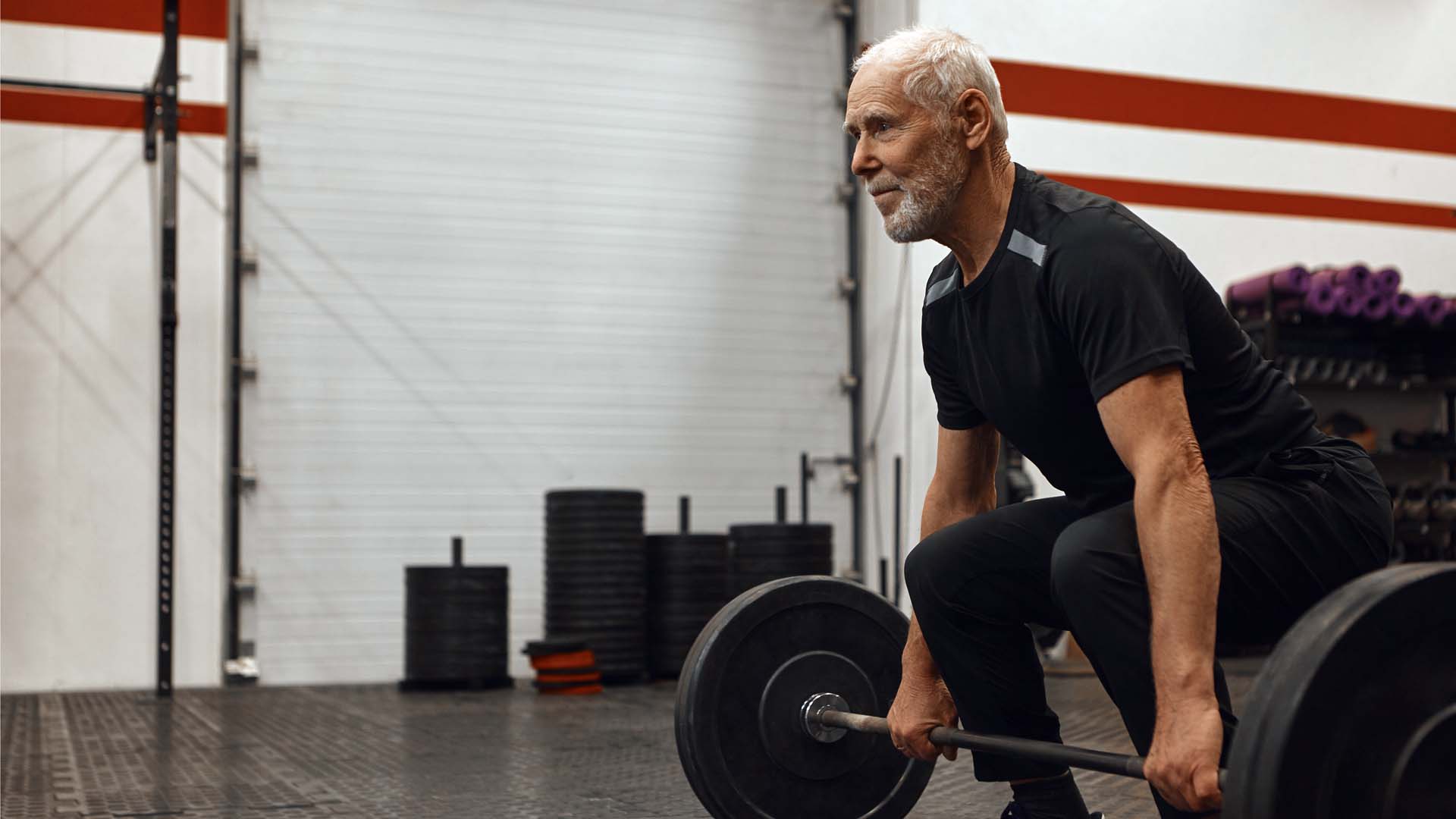 A man preparing to deadlift weights in a gym environment