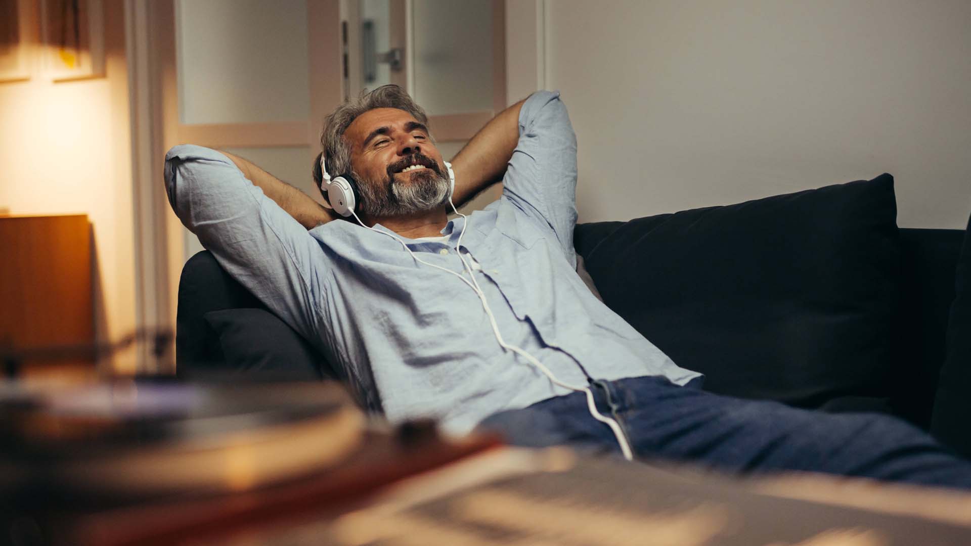 A mature man relaxing in the sofa with headphones on