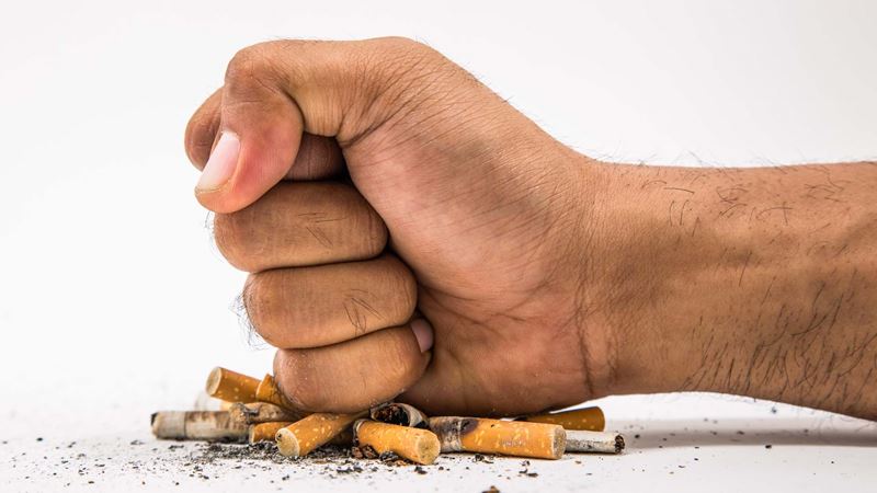 A fist crushing cigarette butts