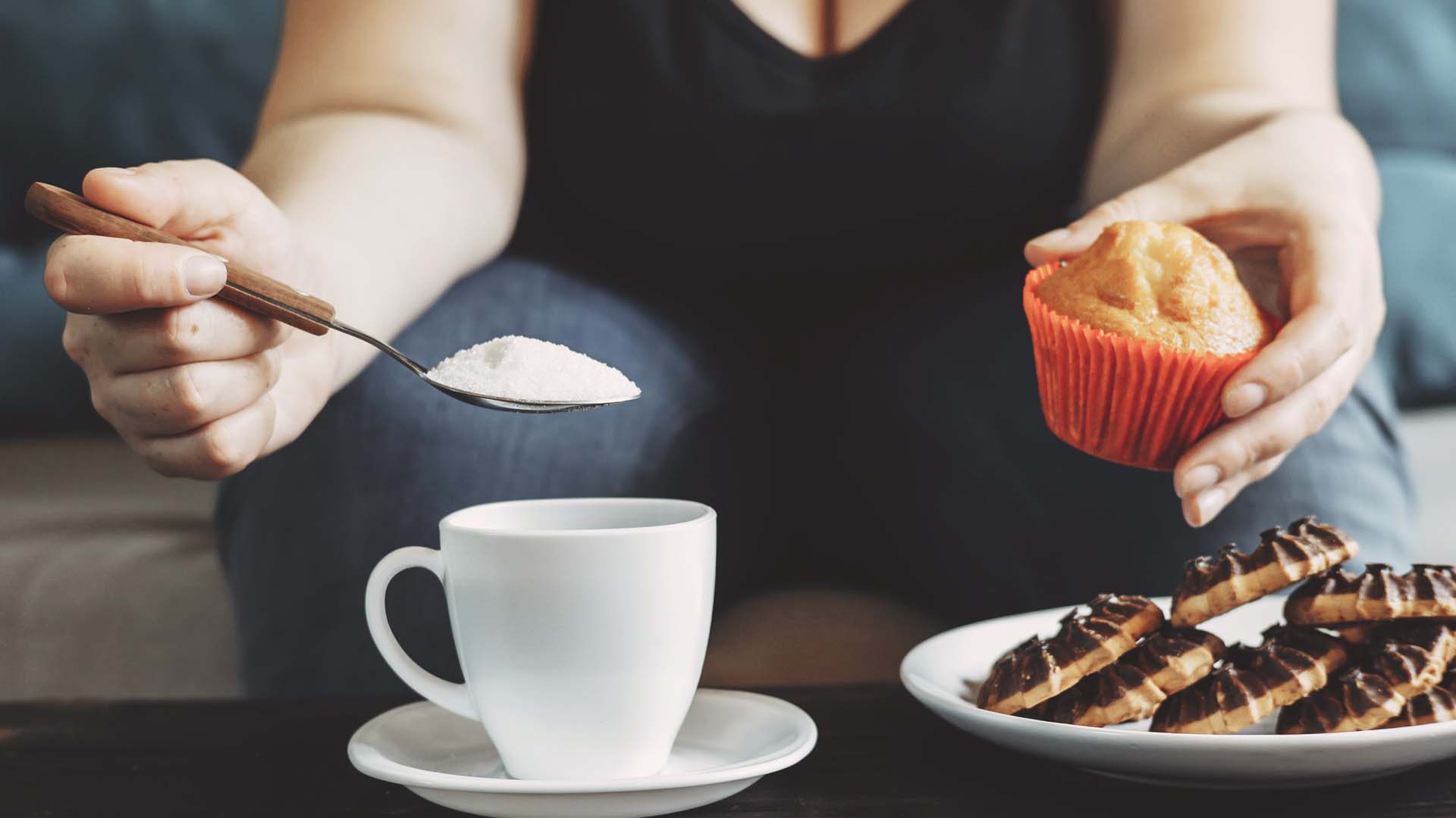 A heaped spoon of sugar over a coffee cup