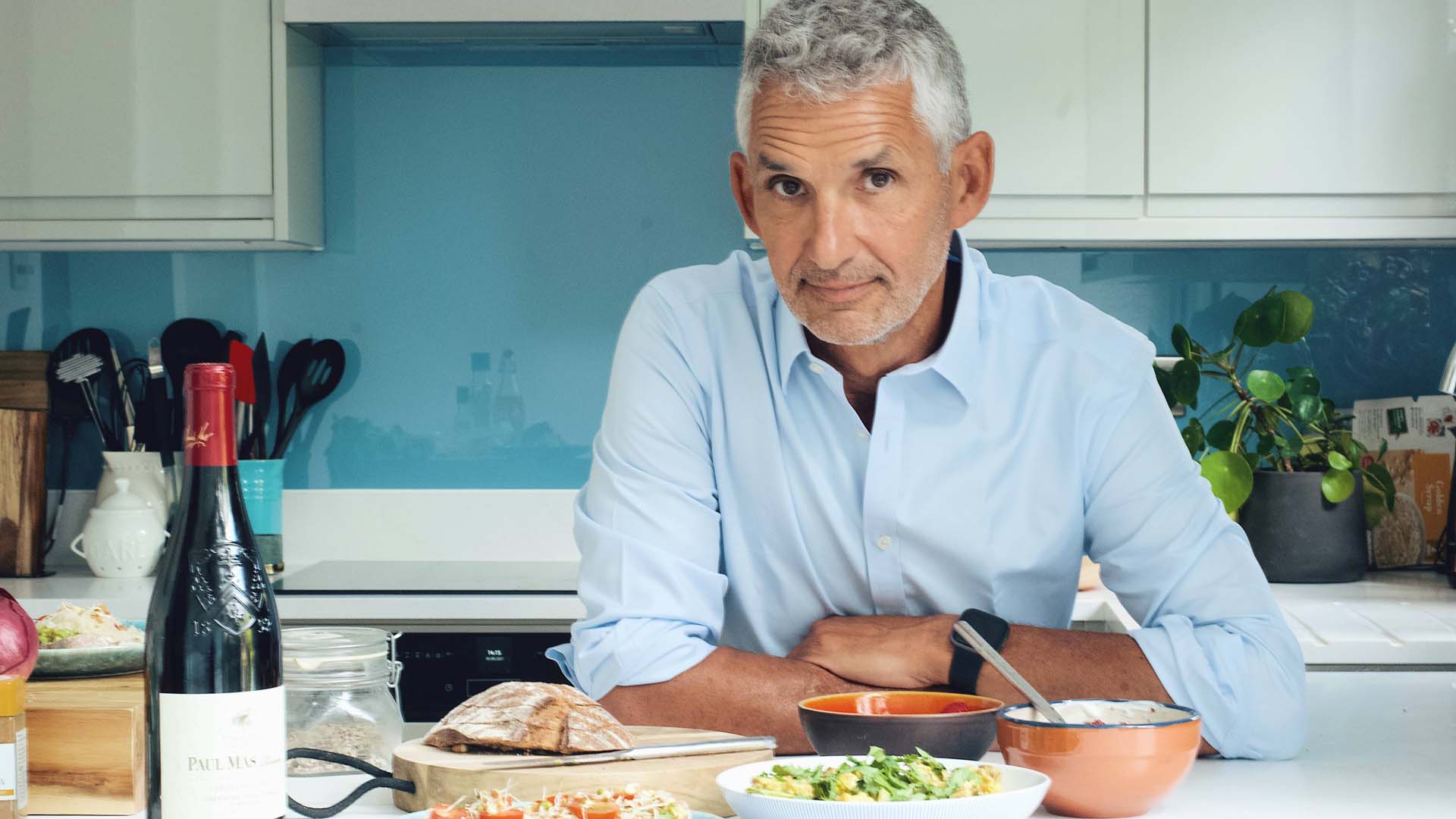 Tim Spector in the kitchen with a glass of wine and dinner