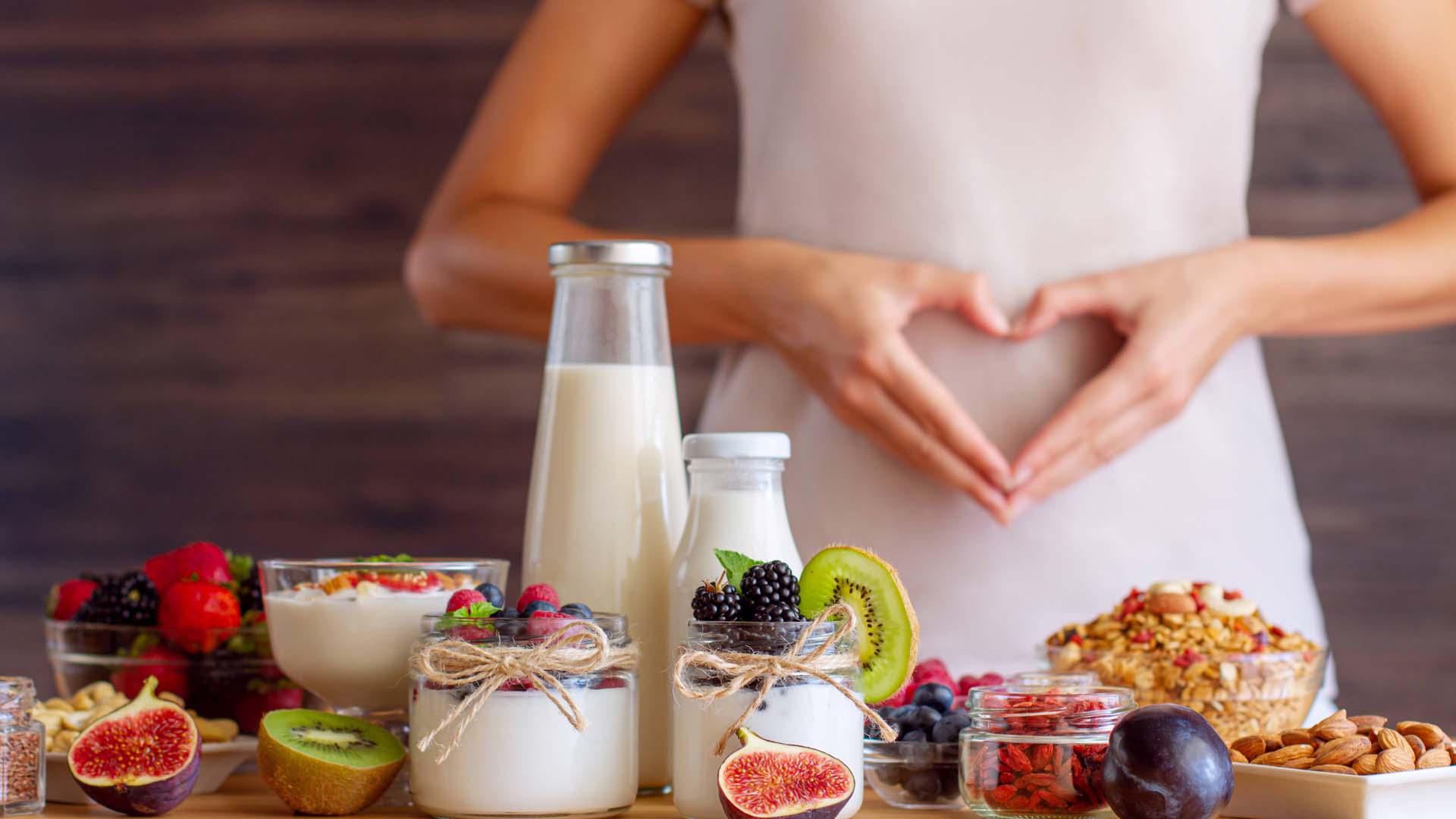 woman standing in front of gut healthy foods making a heart with her hands