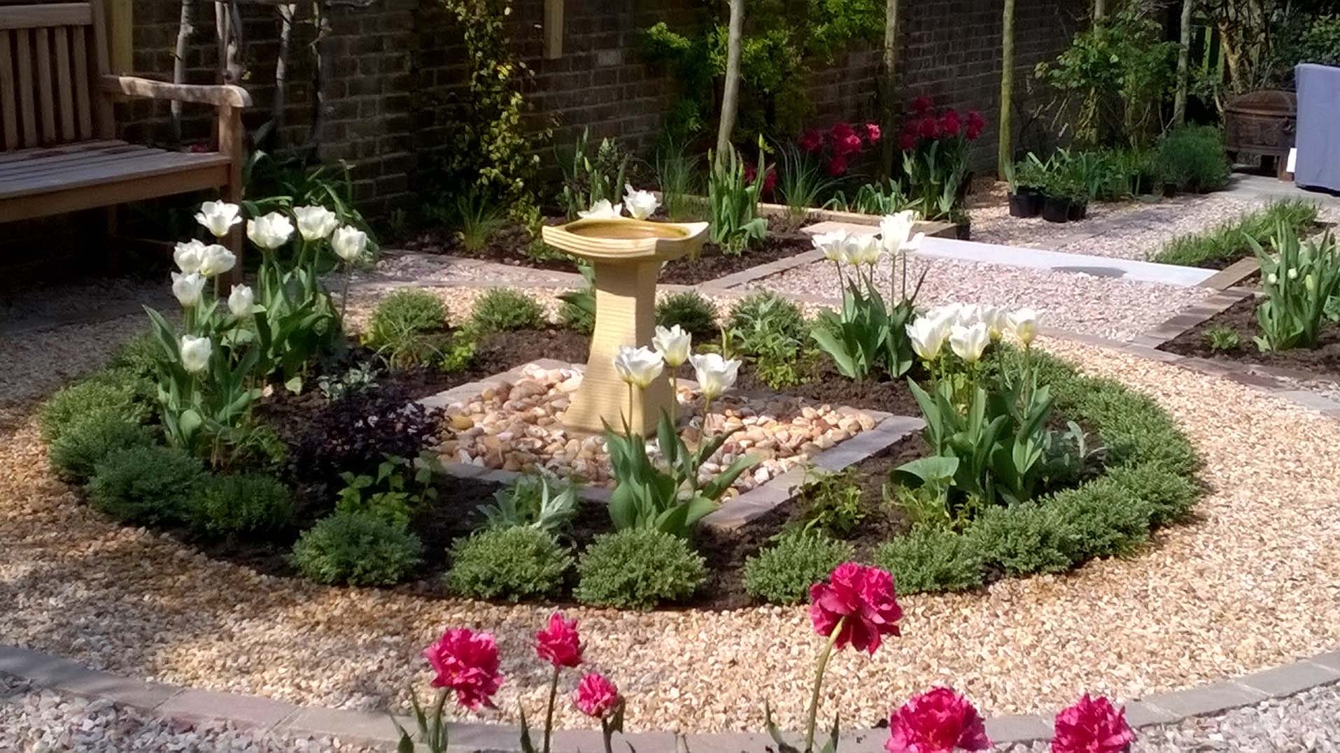 A fountain in the middle of a gravel courtyard