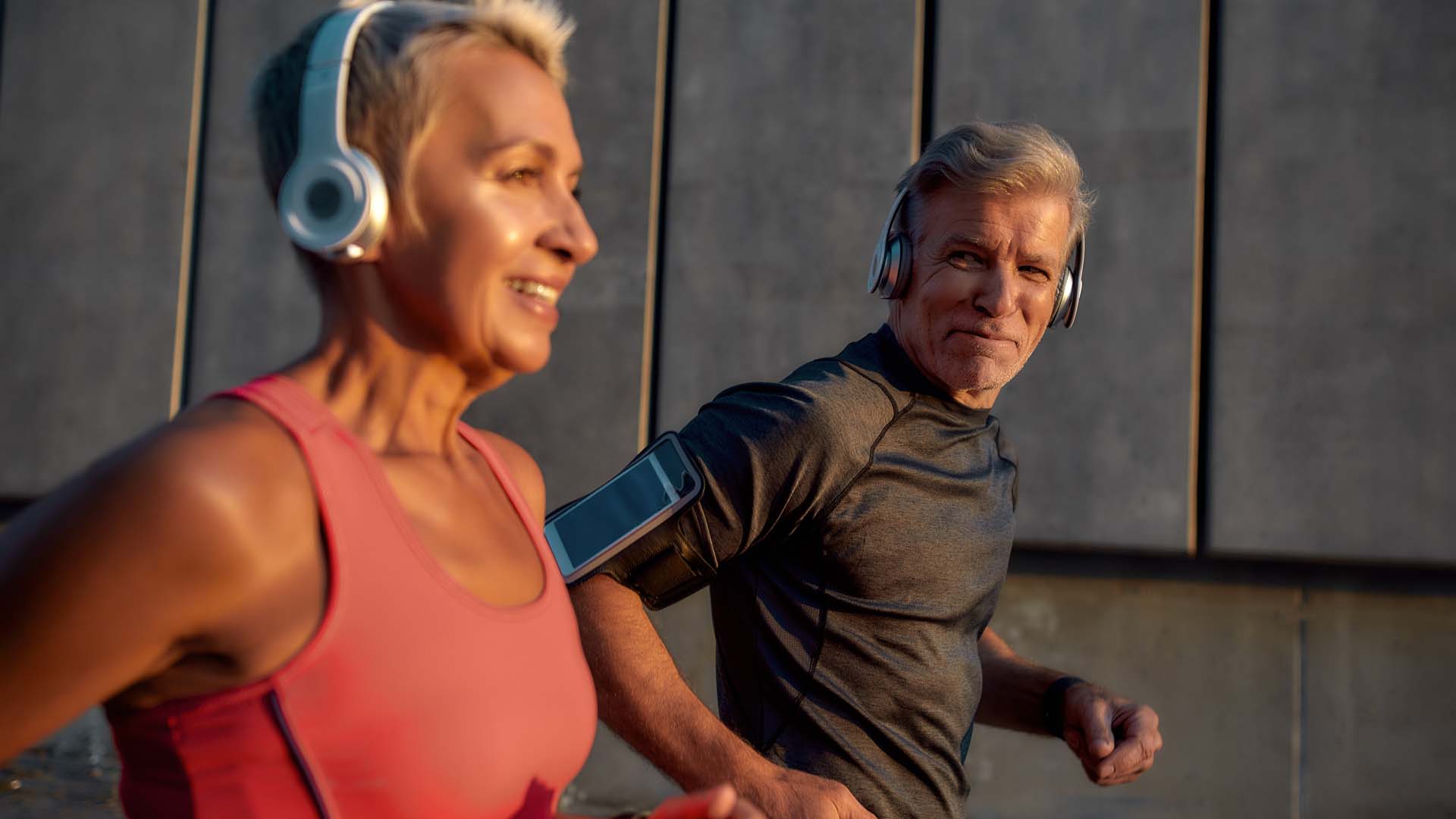A mature man and woman enjoying a jog while wearing headphones