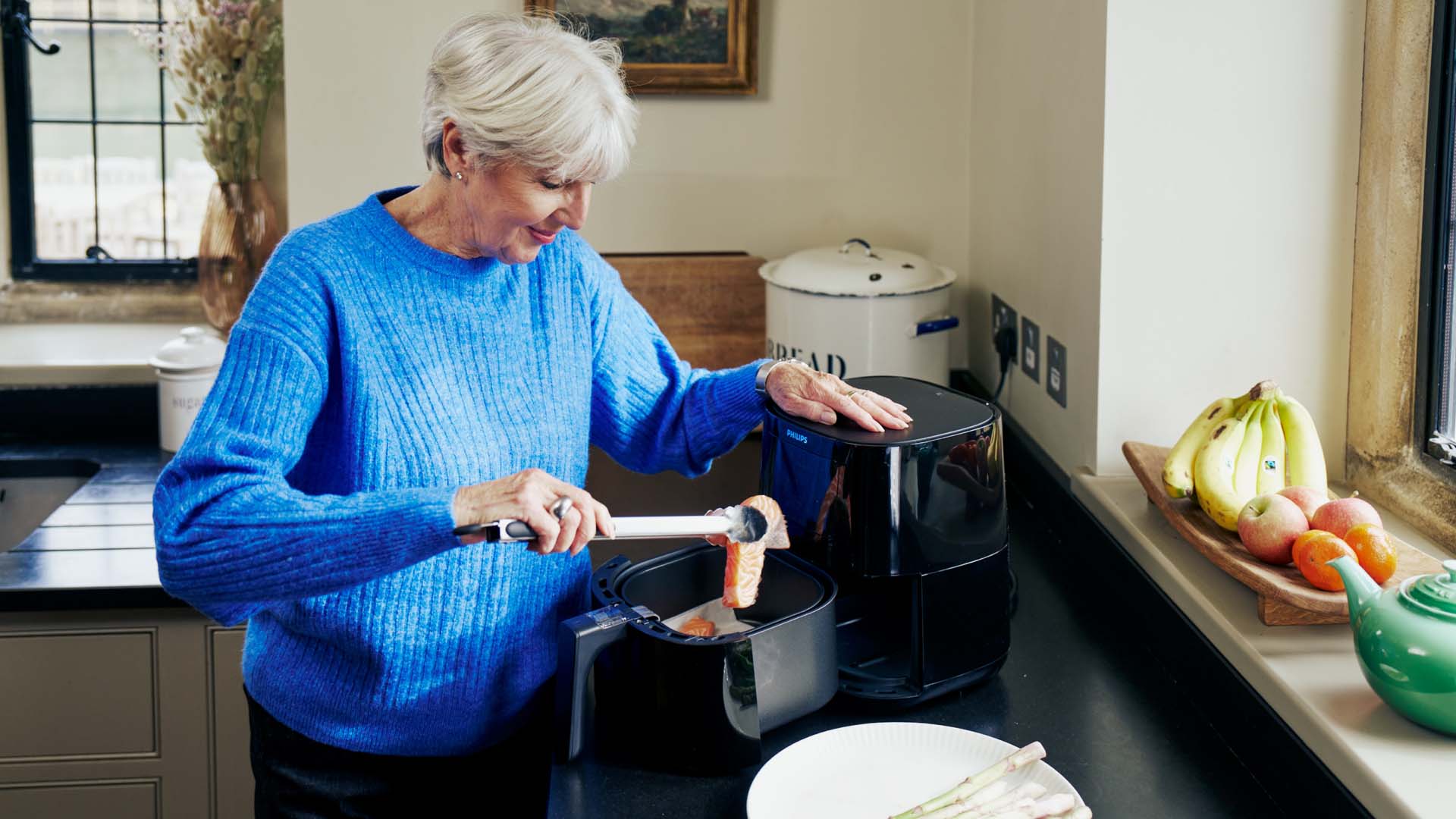 A woman cooking salmon in an air fryer