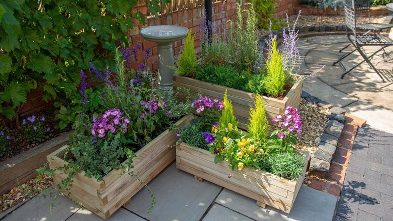 a paved garden with two long wooden planters