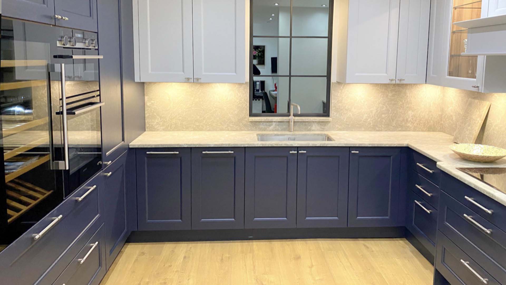 a blue kitchen with under cabinet lighting and a wooden floor