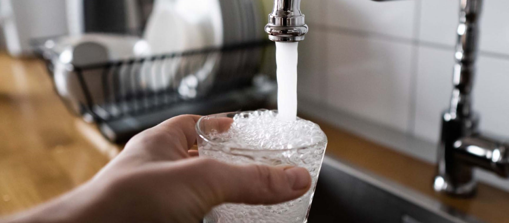 A close up of someone filling a glass of water from a tap | Shutterstock/Jin Odin